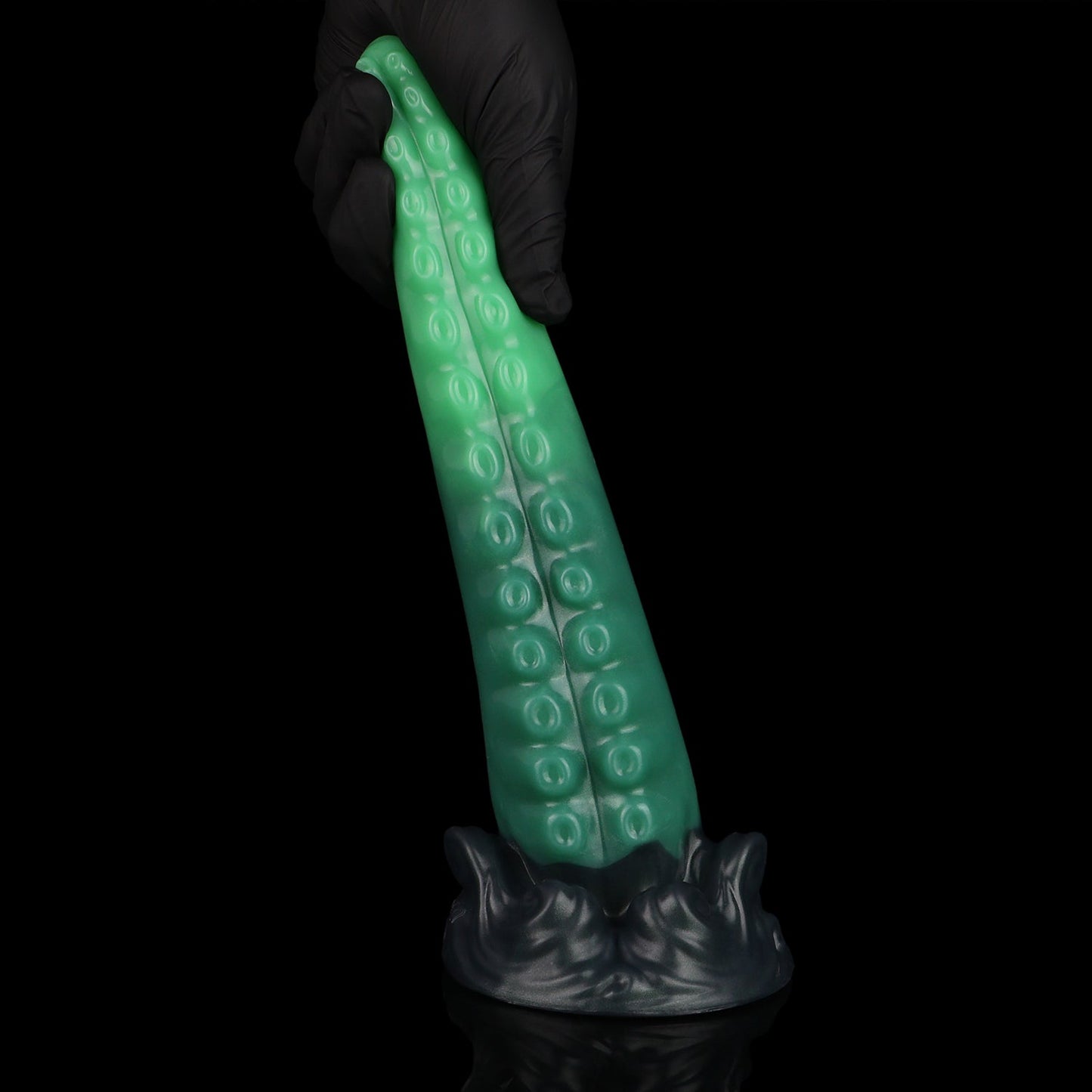 Tendrul the Tentacle dildo, Ogre colorway, held upright in a gloved hand showing the sculpted whirlpool base