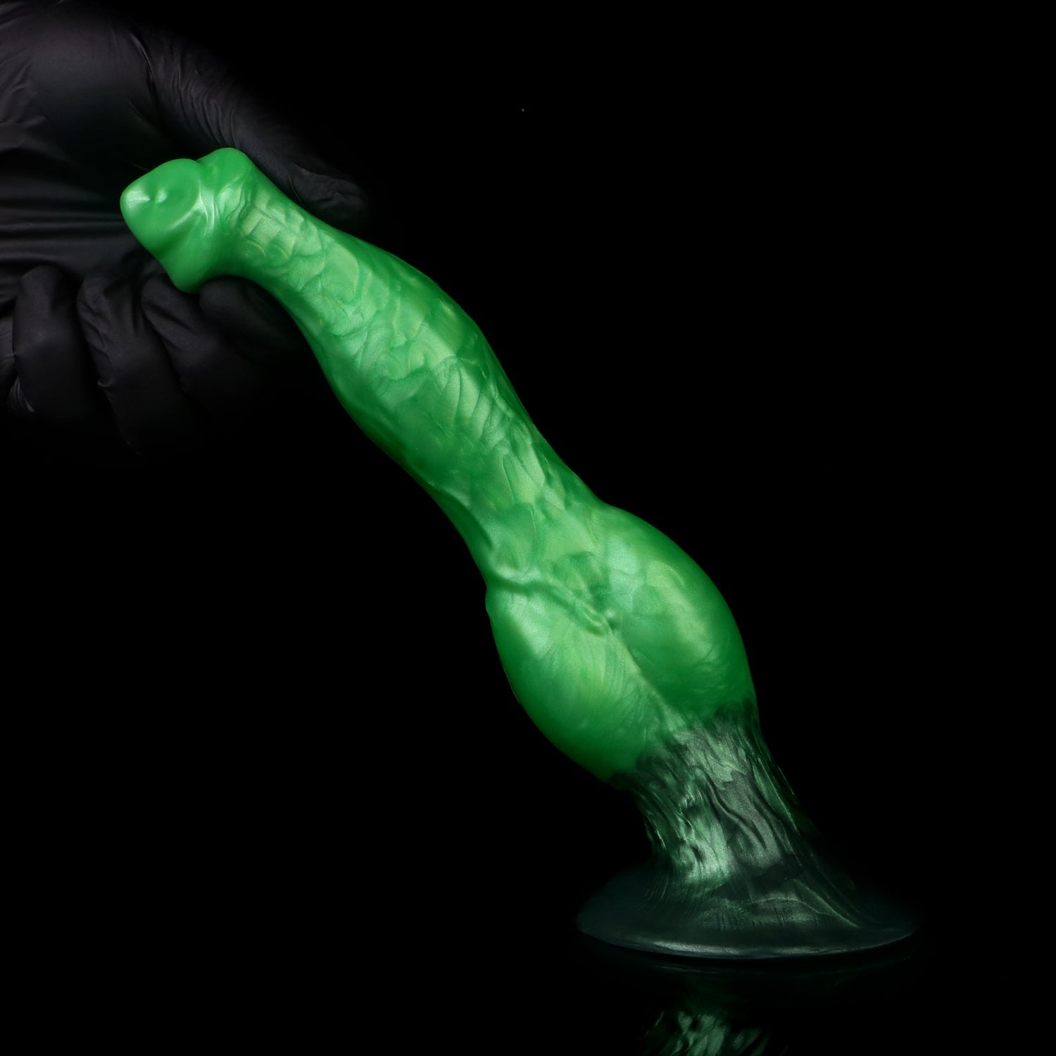 Darkhound the Canine Alpha dildo, Rampage colorway, standing on its base with a gloved hand steadying the tip
