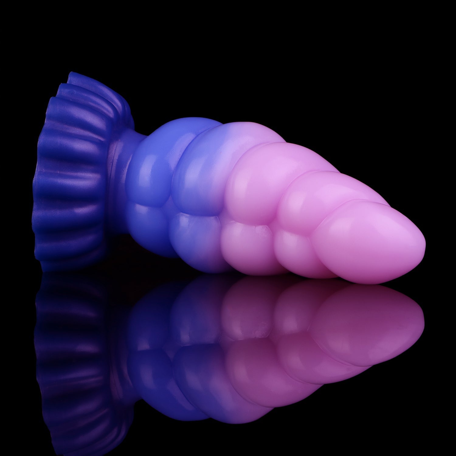 Larval the Alien Spawn dildo, Flux colorway, lying on its side showing the deep indigo-blue base fading into luminous pink at the tip