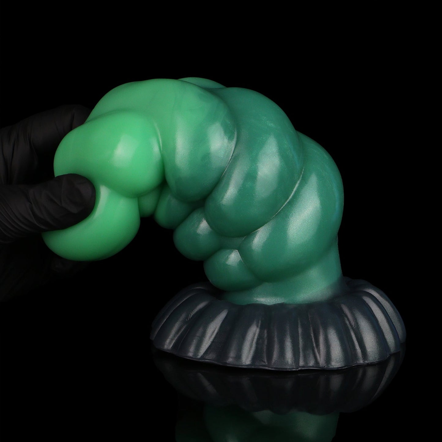 Larval the Alien Spawn dildo, Ogre colorway, gloved hand gripping the tapered green tip