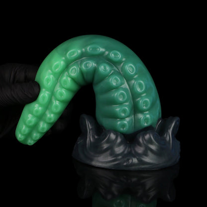 Tendrul the Tentacle dildo, Ogre colorway, standing on its base with the tentacle curled over to show its flexibility
