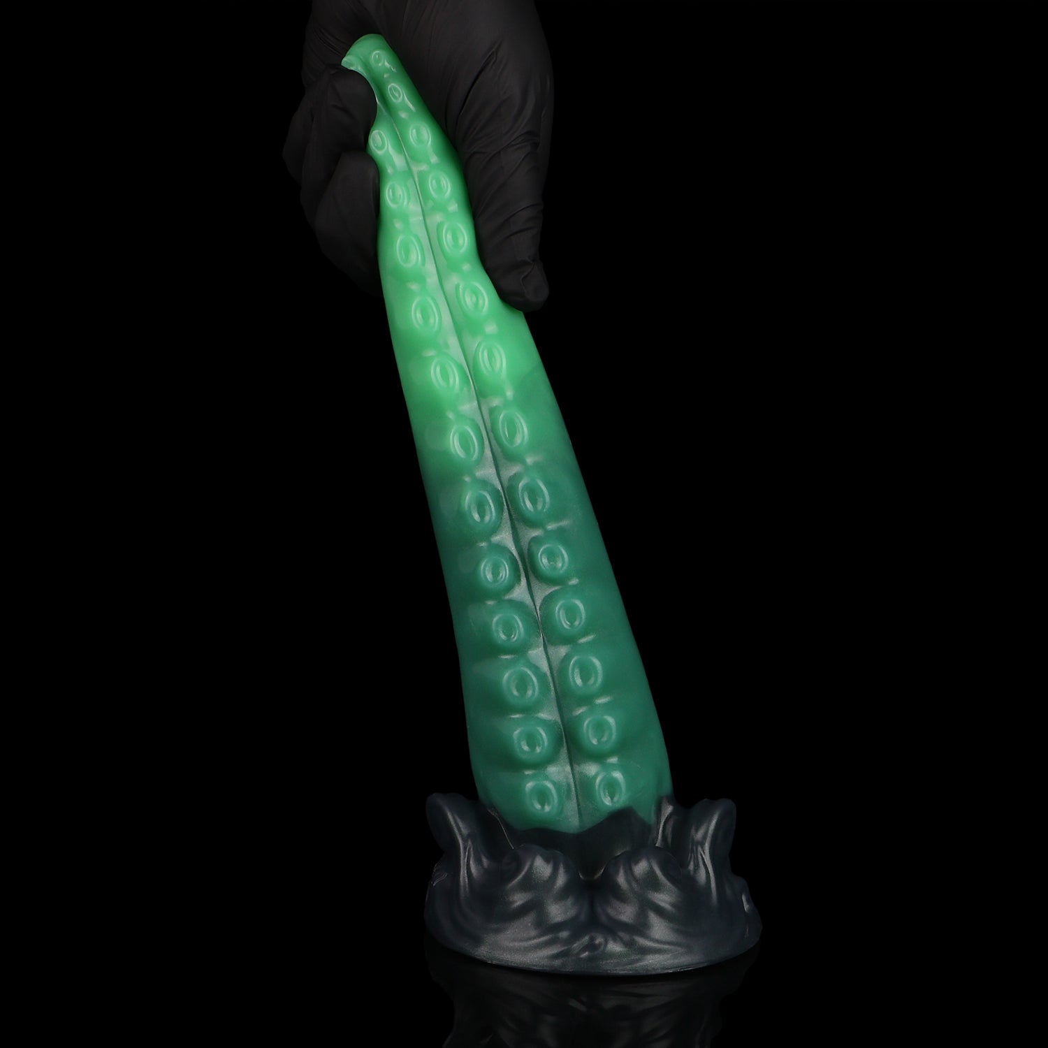 Tendrul the Tentacle dildo, Ogre colorway, held upright in a gloved hand showing the sculpted whirlpool base