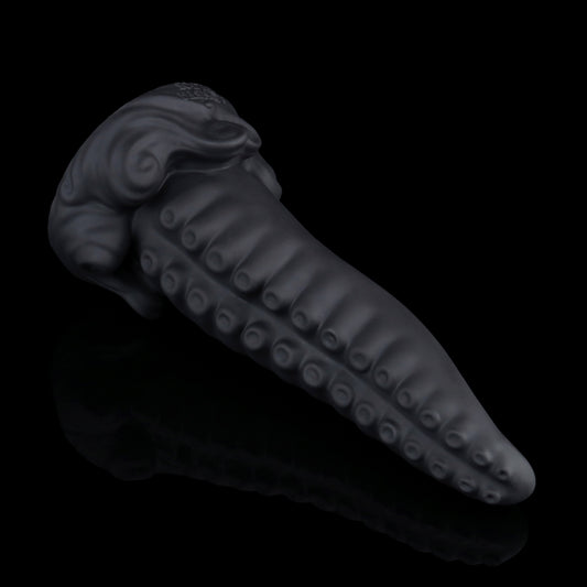 Tendrul the Tentacle dildo, Shadow colorway, lying on its side in full profile showing the tapered tentacle and whirlpool-wave base
